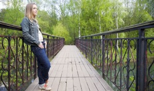 woman thinking whilst standing on a bridge